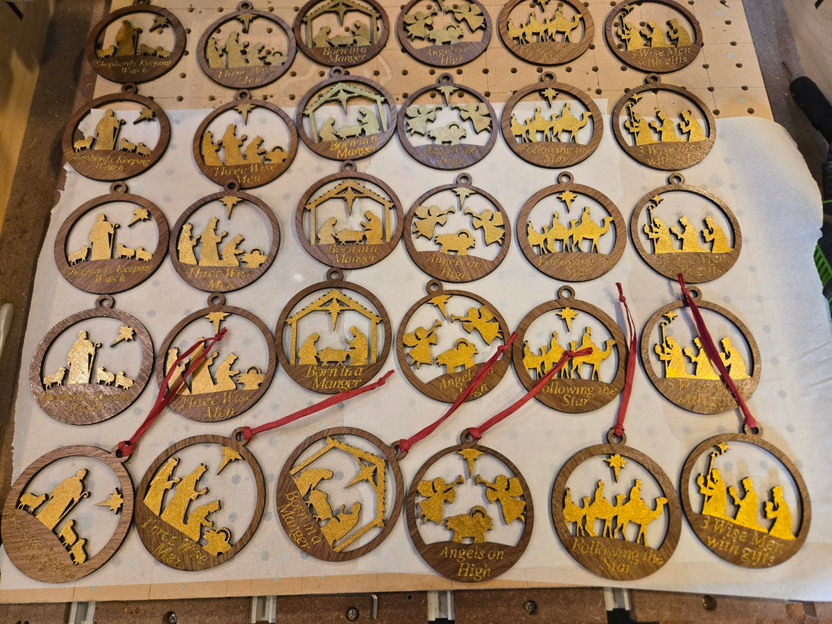 Full collection of laser-cut nativity ornaments laid out showing all available designs