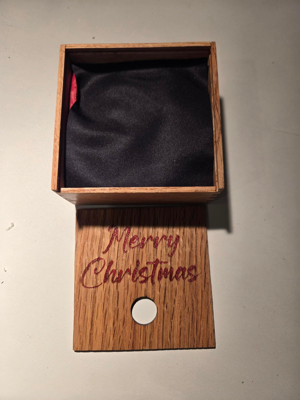 Open engraved gift box showing black fabric lining with red ribbon