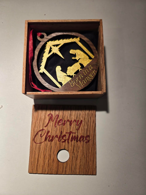 Born in a Manger ornament displayed inside open engraved Merry Christmas gift box