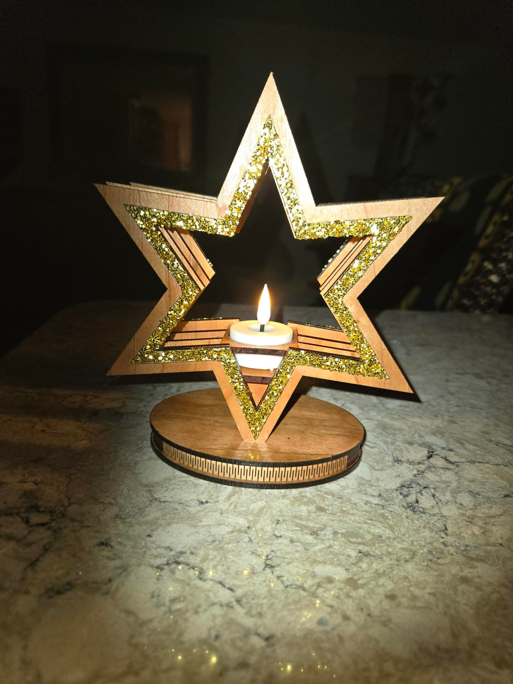 Star candle holder glowing on marble surface in dark setting