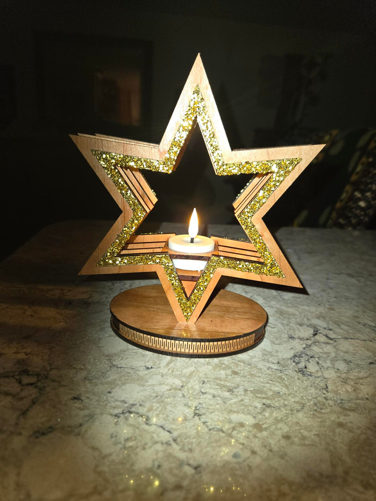 Star candle holder glowing on marble surface in dark setting